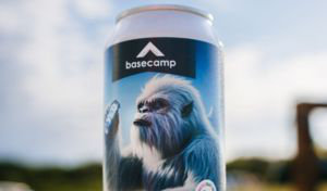 A can of beer sits on a boulder, lit up by the sun. The can is printed with a yeti about to take a sip of its own beer. The can is branded ‘Basecamp’ and the tag line is ‘Unleash the Legend’.