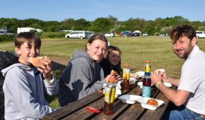A family eating breakfast rolls ourside on a field