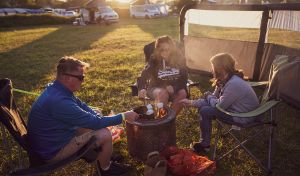 A family sitting around a firepit toasting marshmallows.