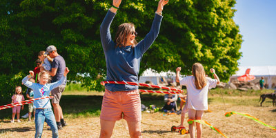 Adult hula hooping outdoors at Mendip Basecamp, family-friendly summer activities in sunshine.