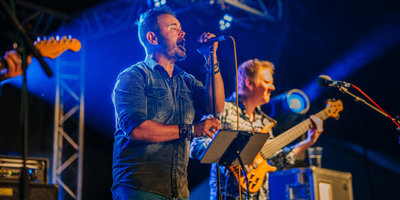 Male performer singing, band mate playing guitar at Mendip Mini Fest weekends at Basecamp.